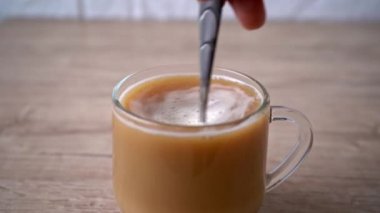 Bir adam bir fincan aromatik kapuçinonun içinde şeker karıştırır. 4k stok görüntüsü.