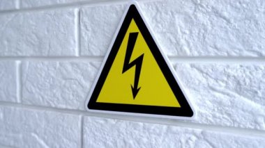 Elektrik tehlikesi sarı arka planda bir işaret. Duvarda bir tehlike işareti asılı. 4k stok görüntüsü.
