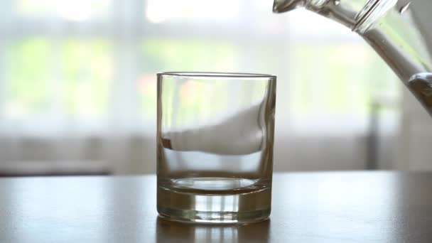 Gros plan mains masculines verser de l'eau dans le verre de cruche à fond de cuisine. Images du stock 4k. — Video