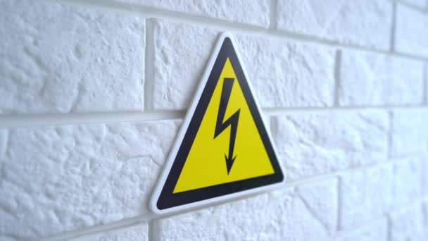 Nebezpečí elektřiny je znamení na žlutém pozadí. Na zdi visí nápis nebezpečí. 4k stock záběry. — Stock video