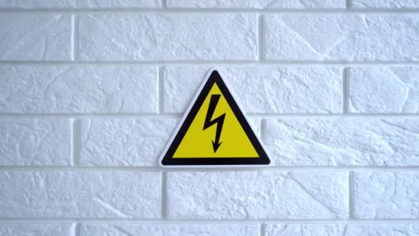 Électricité danger un signe sur fond jaune. Un panneau de danger pend sur un mur. Images du stock 4k. — Video