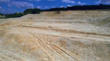 Açık çukur madenciliğindeki kum fabrikasının Arial görüntüsü. Drone kazıcıların üzerinden uçuyor ve traktör ezilmiş taşı ve kayayı çöp kamyonuna yüklüyor. 4k stok görüntüsü.