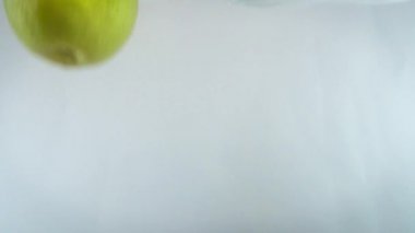 Yakından 4k 'lık elma görüntüsü beyaz sırt çantasına karşı suya düşüyor..