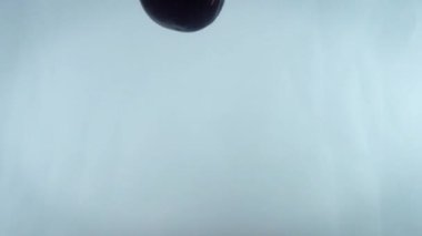 4k 'lık yakın çekim beyaz sırt çantasına karşı suya düşen eriklerin görüntüsü.