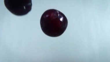 4k 'lık yakın çekim beyaz sırt çantasına karşı suya düşen eriklerin görüntüsü.