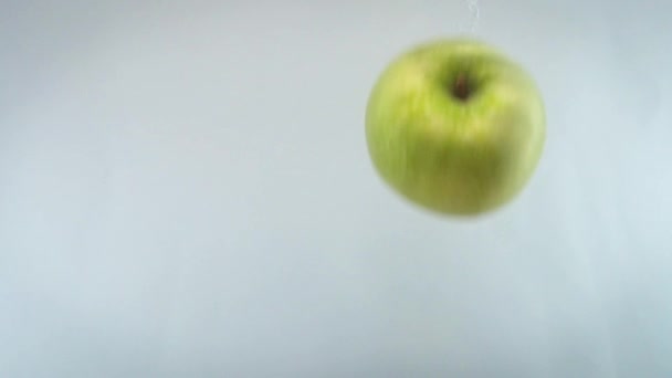 Close-up 4k beeldmateriaal van appels die in het water vallen tegen een witte rug. — Stockvideo