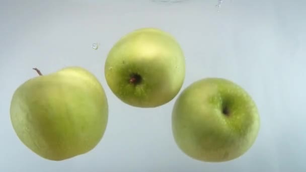 Gros plan 4k images de pommes tombant dans l'eau contre backgorund blanc. — Video