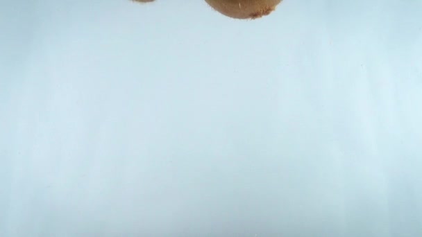 Close-up 4k beelden van kiwi vallen in het water tegen witte rug. — Stockvideo