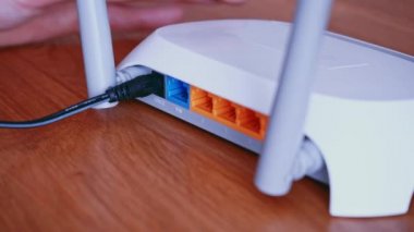 Adam yönlendiriciye ethernet ağ yama kablosu yükle. Masadaki kablosuz yönlendirici, kablolar, kablo kaydıraç görüntüsü. 4K video görüntüleri.