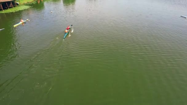 川でカヤックをしている人。カヤックとカヌーのスポーツトレーニングセンター。4kの空撮。夏に川で3つのカヤックを飛ばす. — ストック動画