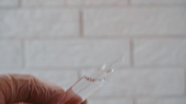 Kadın bilim adamı tehlikeli zehirlere karşı panzehir şişesini dikkatle inceliyor. Şırıngalı ilaç ampulü. 4K video görüntüleri. — Stok video