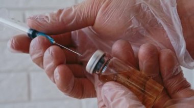 Elleri boş cam şişeden aşı için şırınga dolduruyor. 4K video görüntüleri.