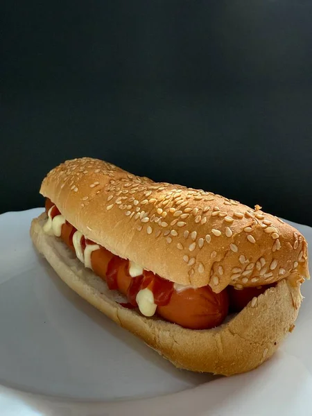 Hot dog with ketchup and mayonnaise on a white plate. Street food.