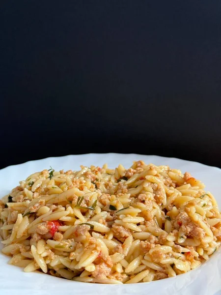 Orzo pasta dish with ground meat and tomato sauce. Plate of orzo pasta with meat sauce.