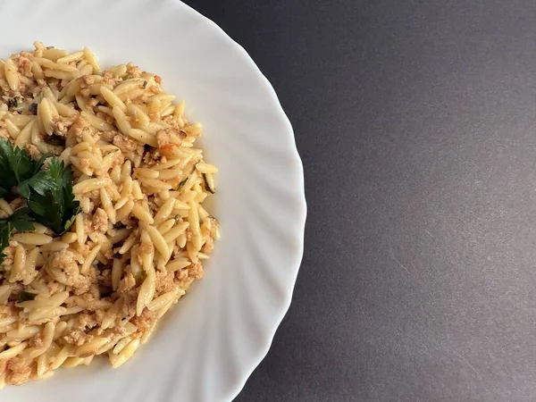 Orzo pasta dish with ground meat and tomato sauce. Plate of orzo pasta with meat sauce.
