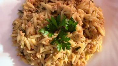 Orzo pasta dish with ground meat and tomato sauce. Plate of orzo pasta with meat sauce.