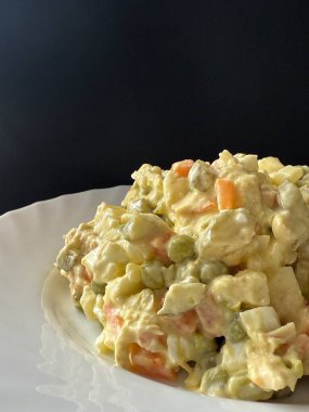 Beyaz tabakta Olivier salatası. Et, haşlanmış sebze, yumurta ve mayonezli ev yapımı salata..