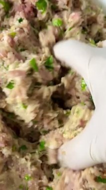 Çiğ eti maydanoz, ekmek, rendelenmiş patates ve baharatla karıştıran bir elin yakın çekimi. Lezzetli, ev yapımı yemekler..