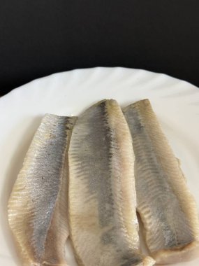 Hafif tuzlu ringa fileto balığının beyaz tabakta yakın çekimi. Sağlıklı, doğal yiyecekler..