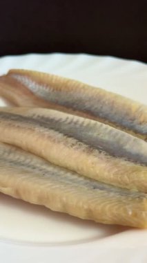 Hafif tuzlu ringa fileto balığının beyaz tabakta yakın çekimi. Sağlıklı, doğal yiyecekler..