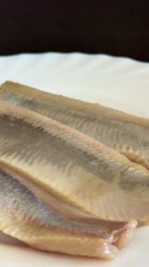 Hafif tuzlu ringa fileto balığının beyaz tabakta yakın çekimi. Sağlıklı, doğal yiyecekler..