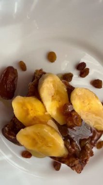 Muz dilimleri, kuru üzüm, hurma ve balla süslenmiş coğrafi bir çikolatalı turta. Lezzetli ev yapımı pişirmeler..