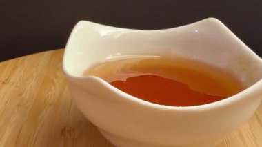 Beyaz bir kaseye yakın plan bal döküldü. Doğal arıcılık ürünü..