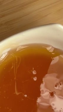 Beyaz bir kaseye yakın plan bal döküldü. Doğal arıcılık ürünü..