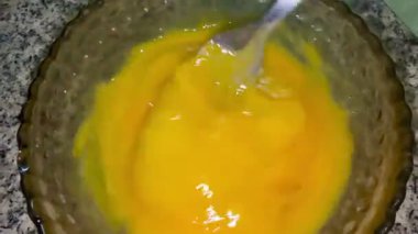 Bir adam eski bir cam kasede çatalla yumurta çırpıyor. Ev yemeği..