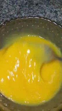 Bir adam eski bir cam kasede çatalla yumurta çırpıyor. Ev yemeği..