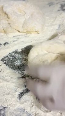 Çiğ hamur yoğururken, keserken ve yoğururken insan elinin makro görüntüsü. Çiğ beyaz un hamurunun yakın plan çekimi. Ev yapımı pişirme..