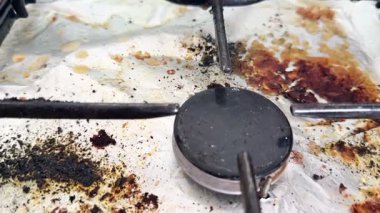 Pişirdikten sonra fırını temizleyen eski kirli bir gaz sobasının yakın çekimi. Ev temizliği.