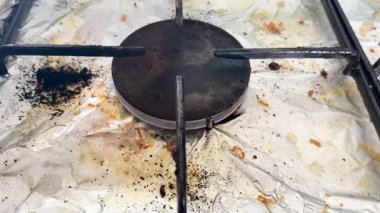 Pişirdikten sonra fırını temizleyen eski kirli bir gaz sobasının yakın çekimi. Ev temizliği.