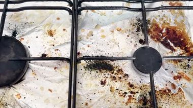 Pişirdikten sonra fırını temizleyen eski kirli bir gaz sobasının yakın çekimi. Ev temizliği.