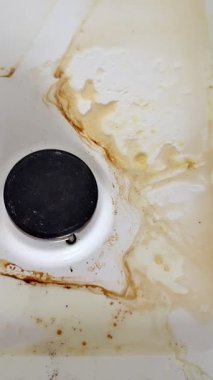 Pişirdikten sonra fırını temizleyen eski kirli bir gaz sobasının yakın çekimi. Ev temizliği.