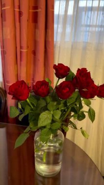 Masadaki vazoda duran bir buket kırmızı gül. Güzel bir gül buketinin yakın çekimi..