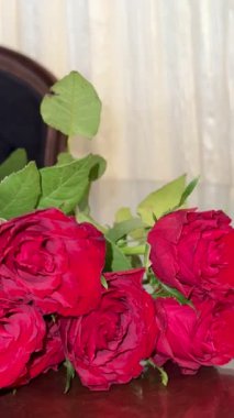 Masanın üzerinde bir buket kırmızı gül yatıyor. Güzel bir gül buketinin yakın plan fotoğrafı..