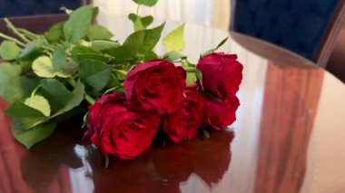 Masanın üzerinde bir buket kırmızı gül yatıyor. Güzel bir gül buketinin yakın plan fotoğrafı..