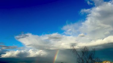 Manzara üzerinde gökkuşağı. Bulutlu gökyüzünün altında gökkuşağı.