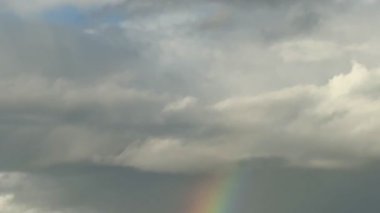 Manzara üzerinde gökkuşağı. Bulutlu gökyüzünün altında gökkuşağı.