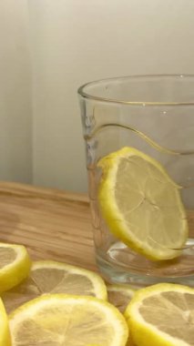 Bir insanın dilimlenmiş limonu bardağa koyup üzerine şeker serptiği yakın plan bir fotoğraf. Taze limon dilimlerini yakın çekim.