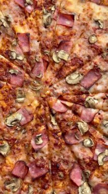 Peynirli, jambonlu ve mantarlı büyük klasik bir pizza. Lezzetli, besleyici ve hızlı bir yemek..