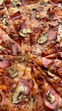 Peynirli, jambonlu ve mantarlı büyük klasik bir pizza. Lezzetli, besleyici ve hızlı bir yemek..