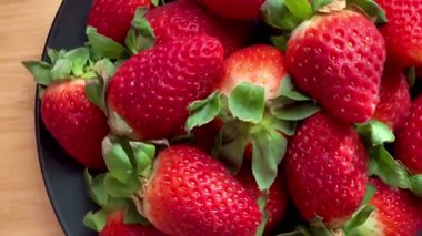 Siyah bir tabağa yerleştirilmiş taze ve büyük çilekleri yakından çek. Lezzetli ve sağlıklı yemekler..