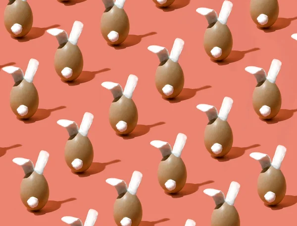 Easter bunny pattern on a red background. Minimal composition. An egg with bunny ears.