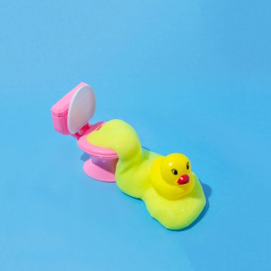 Ördekli sarı salgının çıktığı tuvalet kabı. Hijyenik olmayan şeyleri sunma fikri ile yaratıcı bir kavram. Mavi Arkaplan.