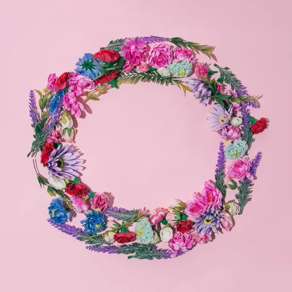 A wreath of spring flowers with space for text. Colorful fresh flowers on a gentle pink background.