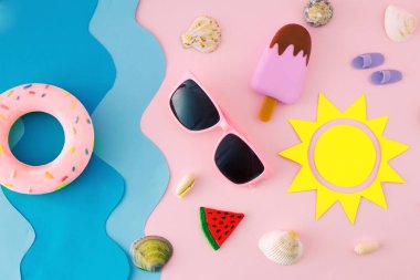 Sahilde güneş, dondurma, kum, deniz kabuğu, güneş gözlüğü ve yüzme lastikleri olan bir yaz sahnesi..