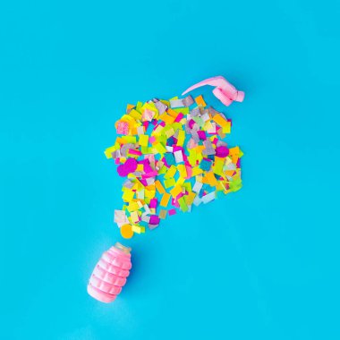 Havaya konfeti atan pembe bir bomba. Kutlama, parti. Mavi arka plan. Minimalizm.