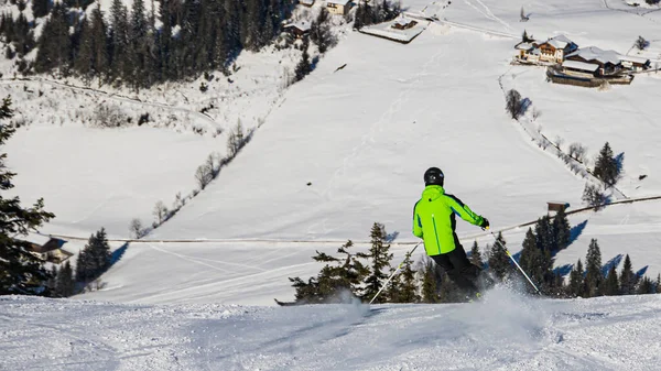 Ski driver making a sharp turn on a terrain edge with flying snow at Flachau, Salzburg, Austria